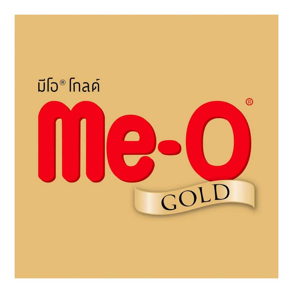 โลโก้ Me-O Gold พื้นหลังสีทอง มีข้อความ “มีโอ โกลด์” สีดำมุมซ้ายบน คำว่า Me-O สีแดงเข้ม พร้อมแถบสีทองคำว่า GOLD อยู่ด้านล่าง